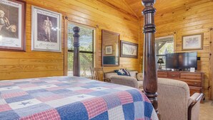 Ein Zimmer mit einem großen Bett, einer Holzbalkendecke, einem Fernseher und gerahmten Bildern an den Wänden.