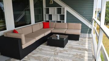 Un espace extérieur aménagé, abrité, avec un canapé d’angle, une table basse et un tapis à motifs.
