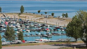 A marina with numerous boats docked, a road with vehicles, and a mountainous backdrop.