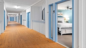 A hotel corridor with wooden flooring, white walls, and blue-framed doors leading to rooms. - Ocean view, unique, stylish, contemporary, upscale condo with a modern ambiance (Hilton Head Island)