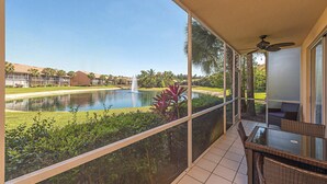 Een balkon met uitzicht op een zwembad, weelderige begroeiing en een gebouw in de verte.