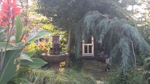 Ein Garten mit einem Steinfbrunnen, einer Holztür und verschiedenen Pflanzen.