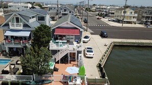 A waterfront property with a dock, a swimming pool, and a covered outdoor seating area. - LBI Bayfront Beauty Brand New Hot Tub! Boat Slip Included! Two blocks to Beach! (Ship Bottom)