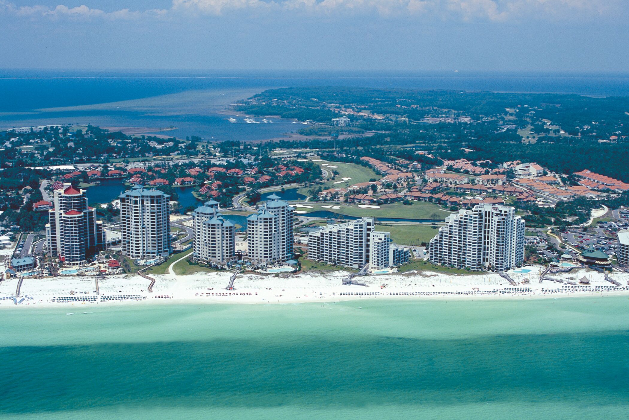Ein Küstenresort mit Hochhäusern, einem Strand und einem Golfplatz.