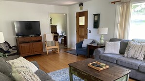 Een woonkamer met een bank, een salontafel, een televisie, een piano en een lamp.