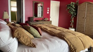 Una camera da letto con un letto, una cassettiera, uno specchio, una porta e una pianta in vaso.