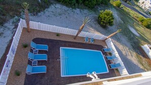 An aerial view of a swimming pool area with lounge chairs and a wooden deck. - Custom Home With Many Extras with beautiful Ocean Views! (Ocean Isle Beach)