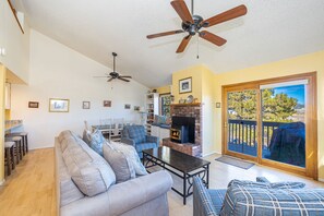 A living room with a sofa, a coffee table, a fireplace, and a ceiling fan.