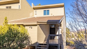 A two-story building with a front entrance, a small porch, and a staircase leading to the second floor.