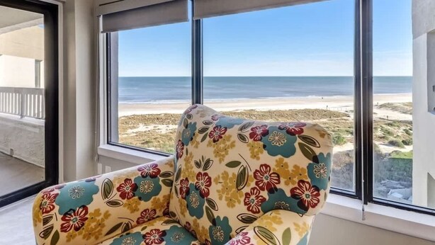Una habitació amb una finestra gran que ofereix vistes a la platja.
