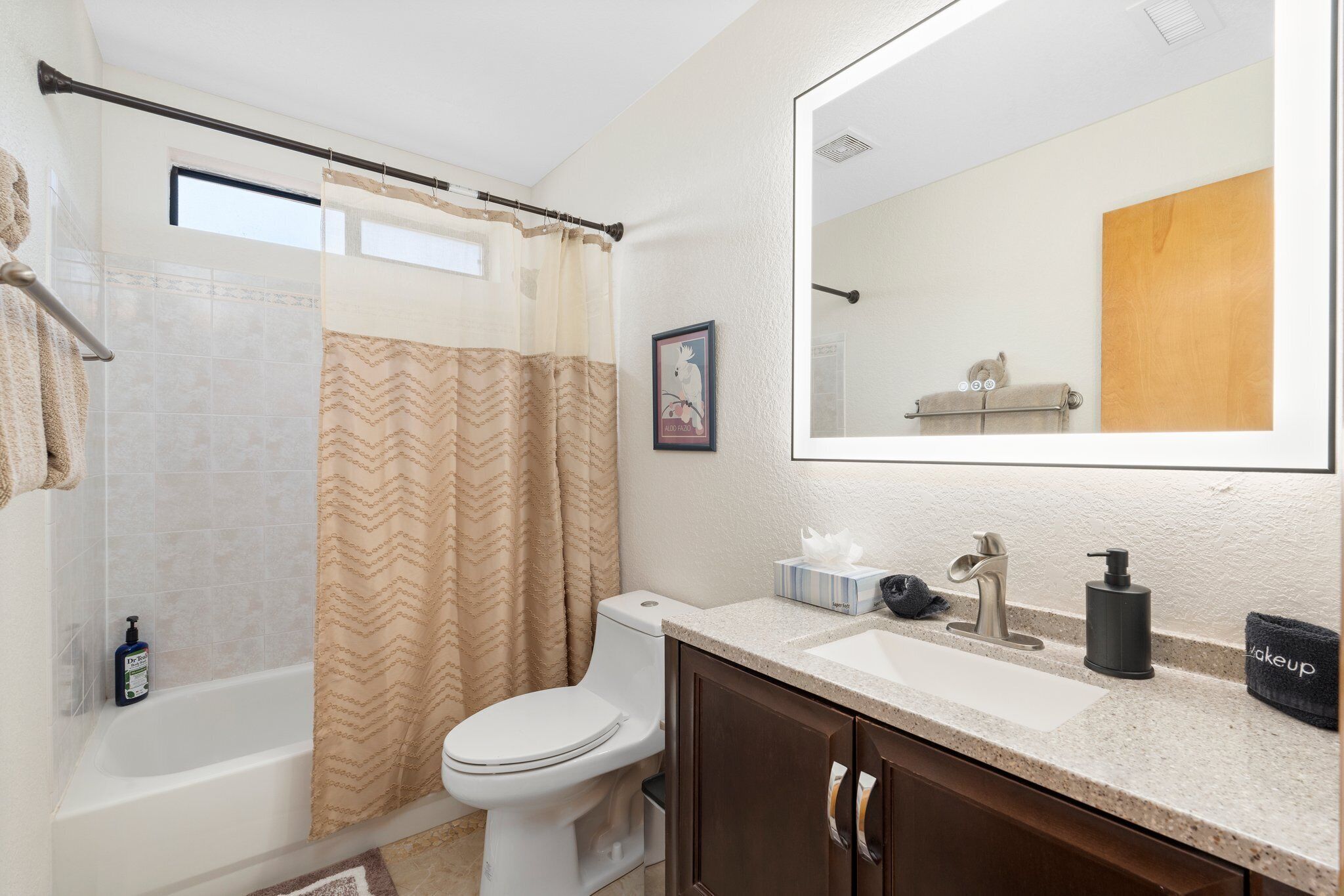 A bathroom with a shower, toilet, sink, and a large mirror.
