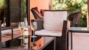 A wicker chair with a white cushion and a glass table with bottles and glasses. - Waterfall, Grapevines and Hot Tub with Views - Nice House Too! (Sedona)