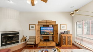 A living room with a fireplace, a television, and a wooden cabinet. - Waterfall, Grapevines and Hot Tub with Views - Nice House Too! (Sedona)