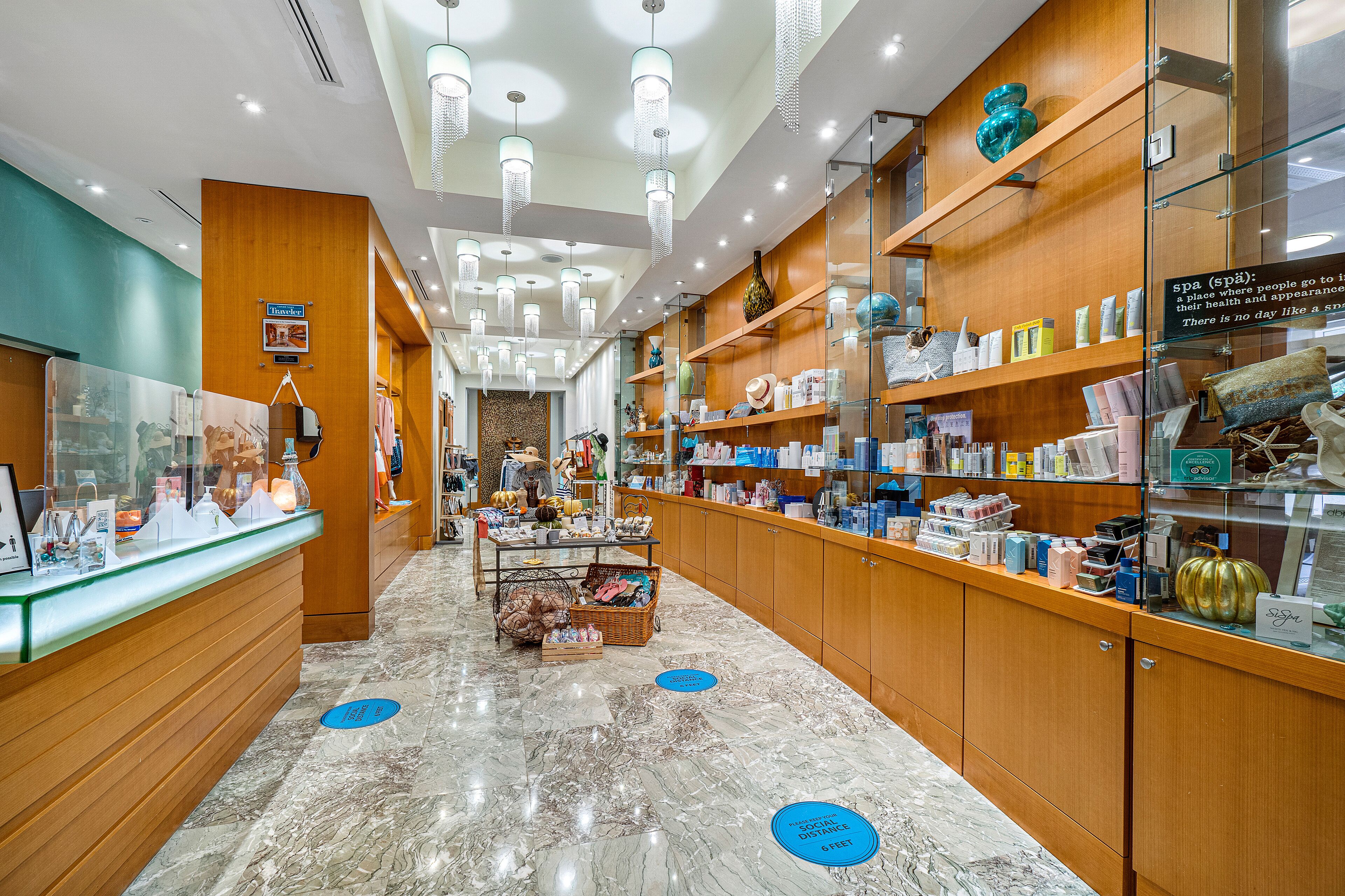 A well-lit spa area with wooden shelves stocked with various spa products, a reception desk, and a marble floor.