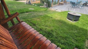 Een houten terras met een bank, een vuurkuil en uitzicht op bergen.
