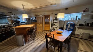 Een keuken met houten vloeren, een centraal eiland en een eettafel met stoelen.