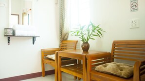Una mesa de madera con sillas, una planta en maceta y un cojín al lado derecho.