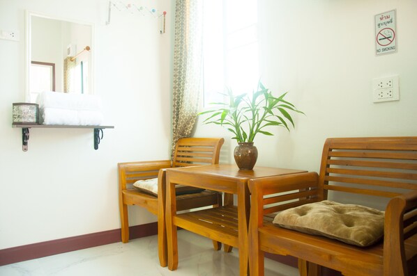 Una mesa de madera con sillas, una planta en maceta y un cojín al lado derecho.
