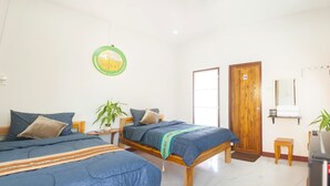 Una habitación con dos camas, una puerta de madera, una mesita y un espejo en la pared.