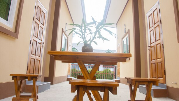 Un pasillo con una mesa de madera y bancos, una planta en maceta y vistas al exterior a través de una ventana.
