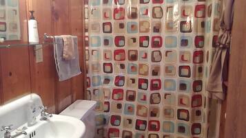 A bathroom with a wooden interior, a white sink, a toilet, and a shower curtain with a geometric pattern.