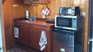Una cocina con gabinetes de madera, un refrigerador, un microondas y un horno tostador.