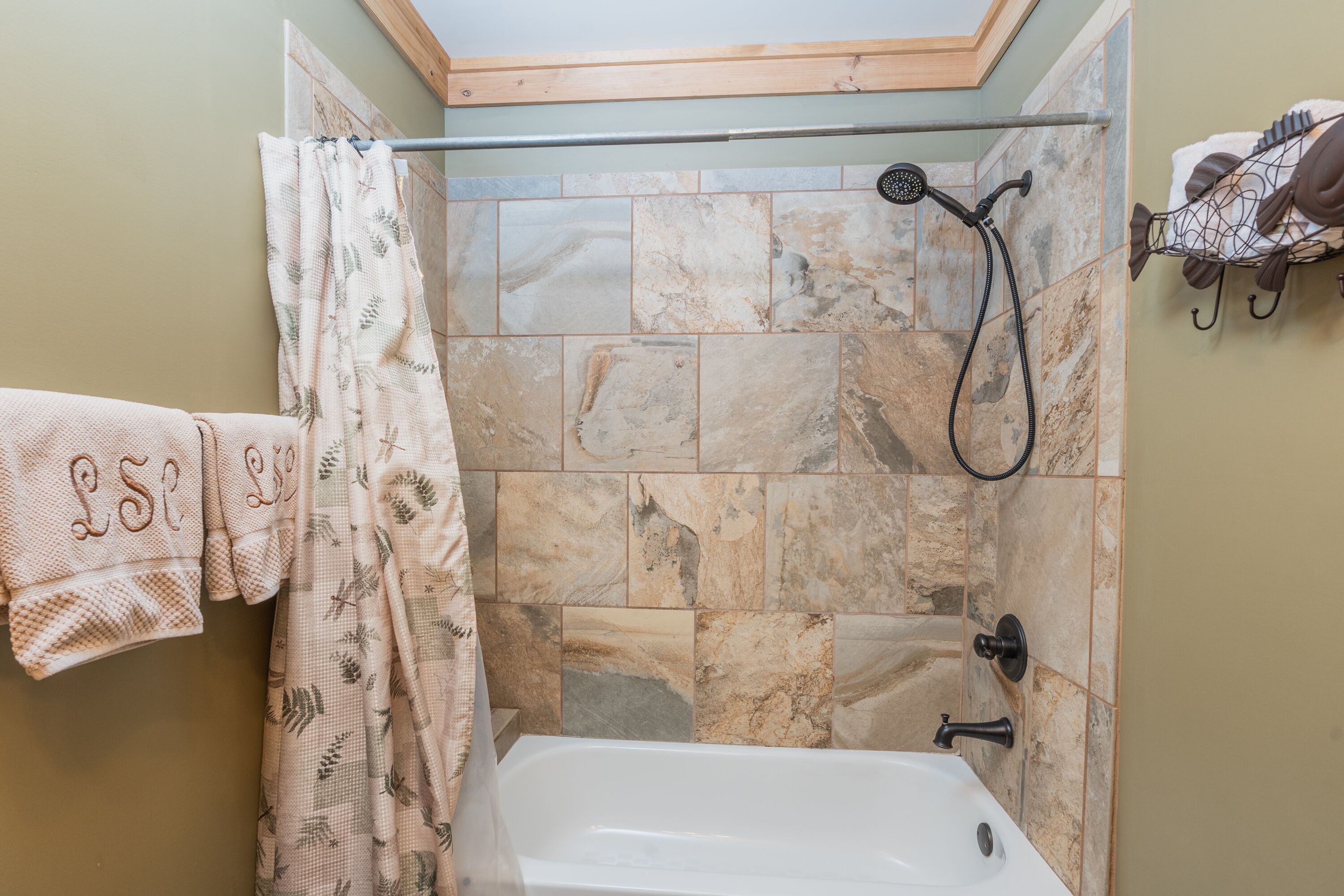A bathroom with a bathtub, shower, and a towel rack with towels.