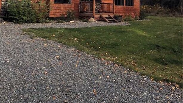 A two-story log cabin with a stone chimney, surrounded by tall trees. - Your "Home Away From Home"-Rustic Alaskan Home (Soldotna)