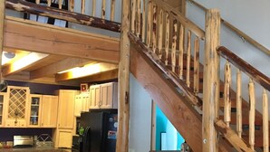 A wooden staircase leading to a lofted area with a kitchen below. - Your "Home Away From Home"-Rustic Alaskan Home (Soldotna)
