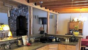A kitchen with a large island, wooden cabinets, and a stone archway. - Your "Home Away From Home"-Rustic Alaskan Home (Soldotna)