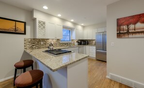 Una cocina moderna con armarios blancos, encimera de granito y electrodomésticos de acero inoxidable.