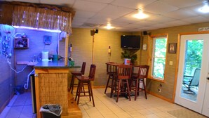 Een restaurant met een houten toonbank, stoelen, een televisie en een deur naar buiten.