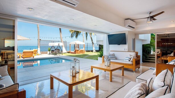 Un salon moderne doté d’une grande porte vitrée donnant sur une zone abritant une piscine, d’un canapé et d’une table basse.