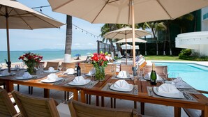 Une table dressée pour un repas, avec vue sur l’océan et une piscine.