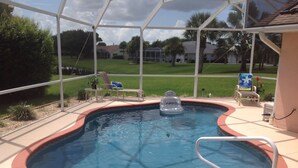 A swimming pool with a hot tub, surrounded by a covered patio area with lounge chairs.