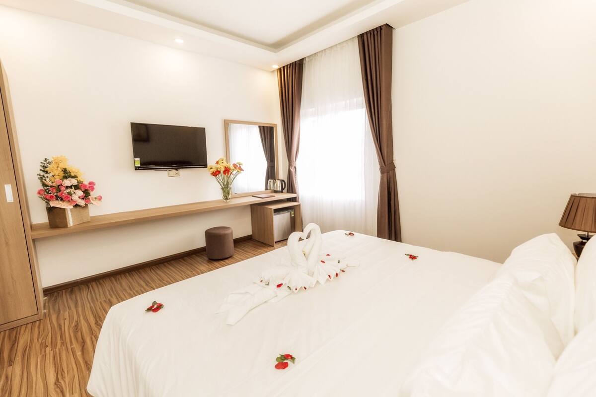 A hotel room with a bed, a TV, a desk, and a mirror.