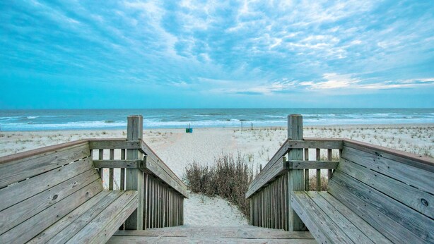 A wooden boardwalk leading to a sandy beach with the ocean in the background. - Immaculate, 4 Bedrooms/4 Bath, w/ Pool, Exterior Elevator and Golf Cart (Emerald Isle)