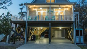 A two-story house with a covered front porch, a staircase leading to the upper level, and a garage. - Immaculate, 4 Bedrooms/4 Bath, w/ Pool, Exterior Elevator and Golf Cart (Emerald Isle)