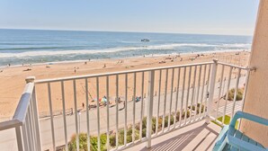 A beach view from a balcony with a railing, sandy beach, and ocean. - Oceanfront & Pool, on the Boardwalk at 37th Street (Virginia Beach)