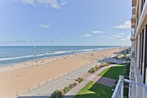 A beach view from a balcony overlooking a sandy beach with a clear sky. - Oceanfront & Pool, on the Boardwalk at 37th Street (Virginia Beach)