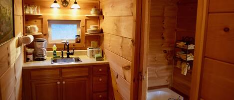 A compact wooden cabin with a kitchenette, a sink, and a bathtub.