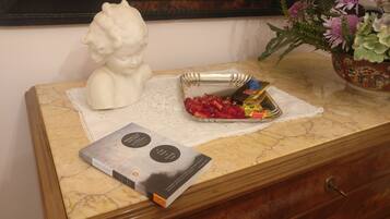 A marble-topped wooden dresser with a white lace doily, a book titled "A Fish Guide to Cooking," a small basket of chocolates, and a decorative bust.