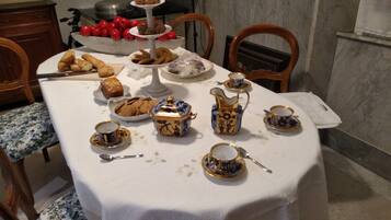 Una mesa de comedor servida con diversos pasteles, galletas y vajillas de té.