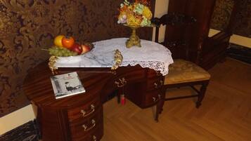 A wooden desk with a lace tablecloth, a fruit bowl, and a decorative vase.