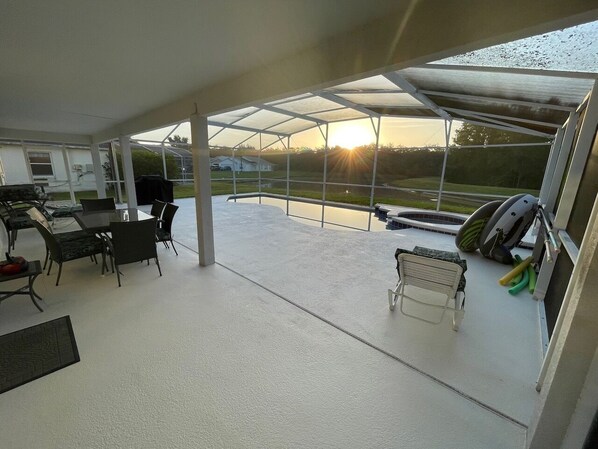 A spacious indoor area with a large glass window overlooking a landscape. There is a dining table with chairs and a small seating area with a bench. - Family-Friendly Vacation Villa Near Disney – Space, Comfort & Fun for Everyone (Clermont)