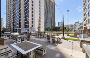 An outdoor patio area with tables and chairs, surrounded by high-rise buildings.