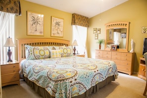 Un dormitorio con cama, mesitas de noche, cómoda, espejo y decoración en la pared.