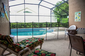 Zona de piscina exterior cubierta con sillones de descanso y una mesa.