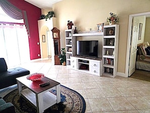 Una sala de estar con televisor, estanterías, un reloj y una puerta.