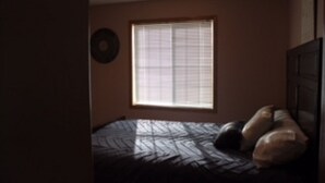 Een slaapkamer met een bed, een raam en een klok aan de muur.